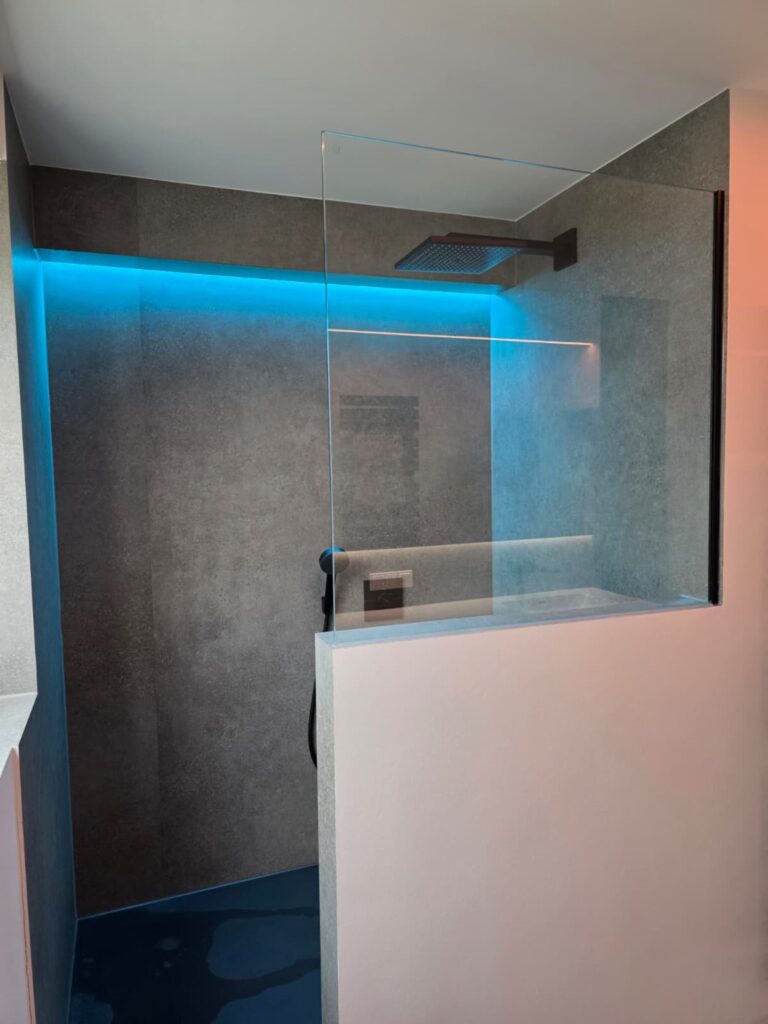 Man sieht eine barrierfreie Dusche mit fugenlosen Wandplatten