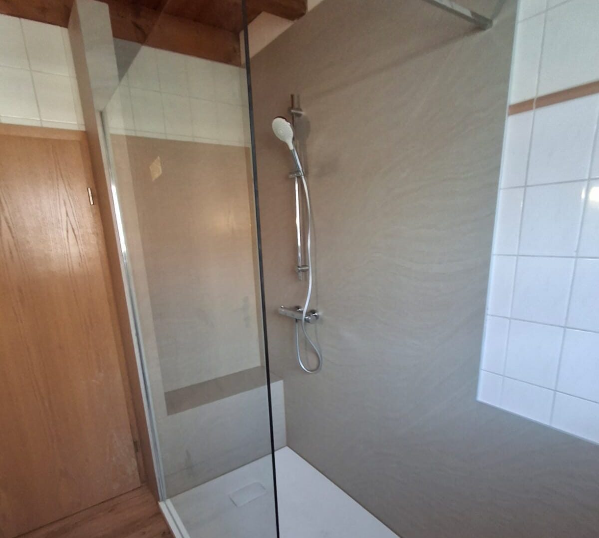 Barrierearme Dusche mit Duschwand aus Glas und niedriger Duschwanne mit fugenlosen grauen Platten